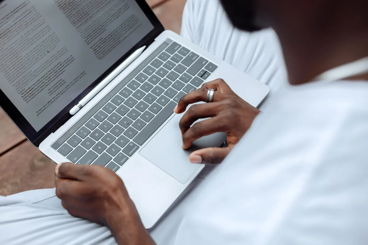 A person reading a text-heavy article on a laptop resting on their lap